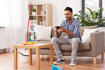 Image showing man playing game on smartphone after cleaning home