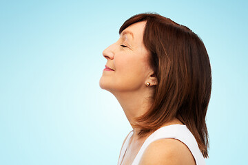 Image showing profile of smiling senior woman over blue