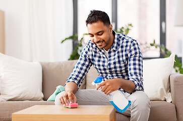 Image showing indian man cleaning table with detergent at home