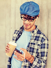 Image showing man with earphones and smartphone drinking coffee