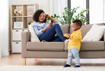 Image showing mother using smartphone and baby playing toy car