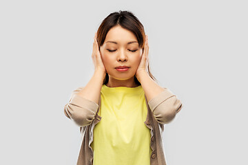 Image showing asian woman closing ears by hands