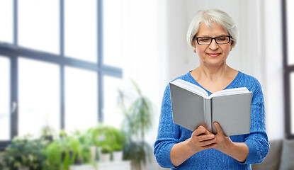 Image showing senior woman in glasses reading book at home