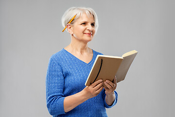 Image showing senior woman with pencil and diary or notebook