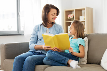 Image showing happy girl with mother reading book at home