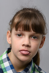 Image showing Portrait of a ten-year-old girl sticking out her tongue from resentment, European appearance, close-up