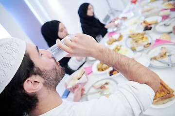 Image showing Muslim family having Iftar dinner drinking water to break feast