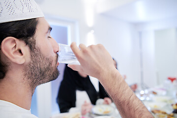 Image showing Muslim family having Iftar dinner drinking water to break feast