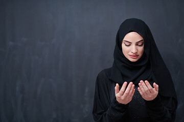 Image showing muslim woman making traditional prayer to God in front of black 