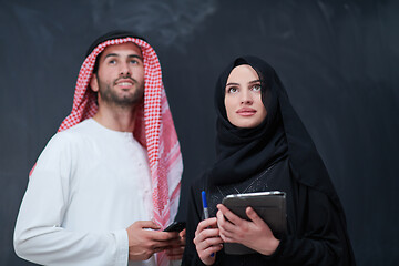 Image showing muslim couple using modern technology in front of black chalkboa