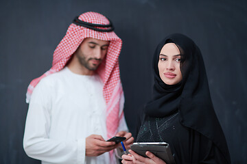 Image showing muslim couple using modern technology in front of black chalkboa