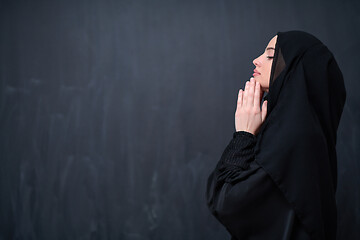 Image showing muslim woman making traditional prayer to God in front of black 