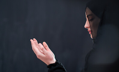 Image showing muslim woman making traditional prayer to God in front of black 