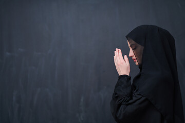 Image showing muslim woman making traditional prayer to God in front of black 