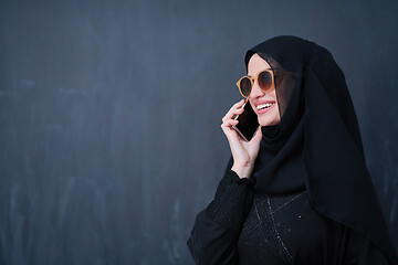 Image showing young muslim woman wearing sunglasses using smartphone