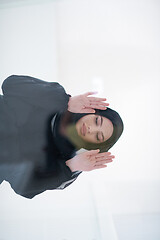 Image showing young arabian muslim woman praying on the glass floor at home