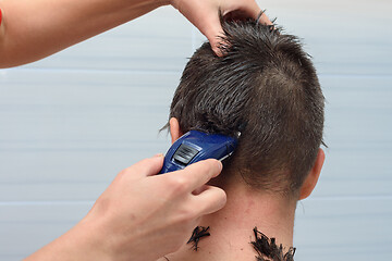 Image showing Hairdresser cut half the hair on the back of the head of a man at home