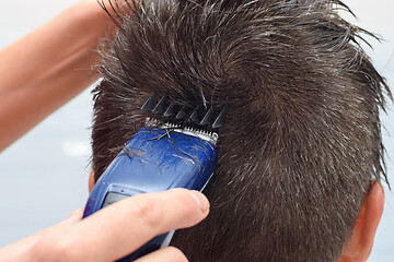 Image showing Hairdresser cuts the hair on the top of the head, close-up