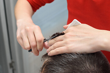 Image showing Hairdresser smooths hairstyle for client, working at home