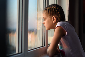 Image showing Eleven-year-old girl in isolation from boredom looks out the window