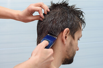 Image showing The hairdresser begins to cut the hair on the mans head at home