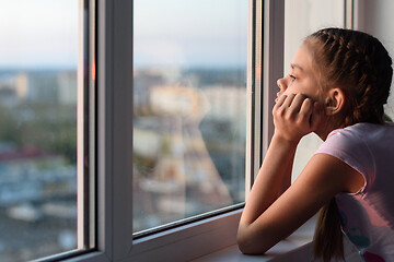 Image showing The girl in self-isolation looks out the window