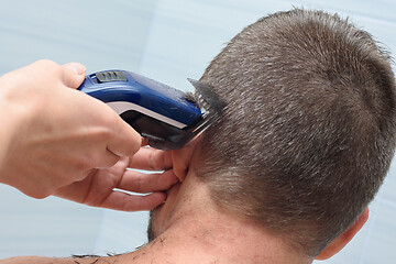 Image showing Hairdresser smoothes and shortens the hair on the man\'s head in the bathroom