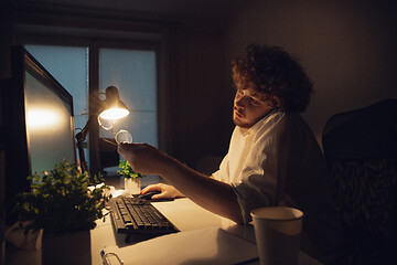 Image showing Man working in office alone during coronavirus or COVID-19 quarantine, staying to late night