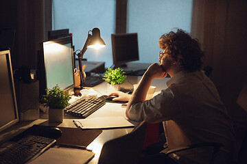 Image showing Man working in office alone during coronavirus or COVID-19 quarantine, staying to late night