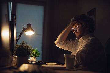 Image showing Man working in office alone during coronavirus or COVID-19 quarantine, staying to late night