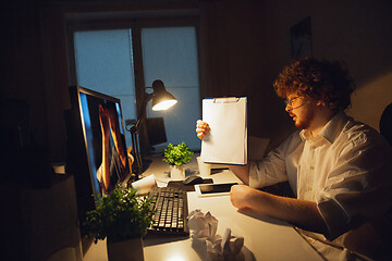 Image showing Man working in office alone during coronavirus or COVID-19 quarantine, staying to late night