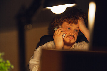 Image showing Man working in office alone during coronavirus or COVID-19 quarantine, staying to late night