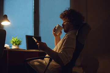 Image showing Man working in office alone during coronavirus or COVID-19 quarantine, staying to late night