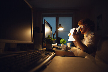 Image showing Man working in office alone during coronavirus or COVID-19 quarantine, staying to late night