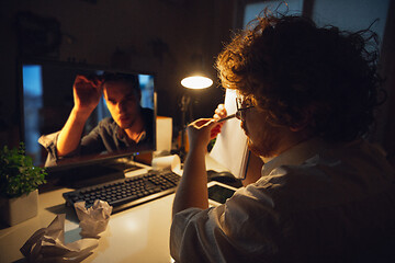 Image showing Man working in office alone during coronavirus or COVID-19 quarantine, staying to late night