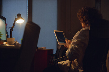 Image showing Man working in office alone during coronavirus or COVID-19 quarantine, staying to late night