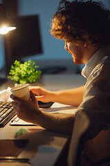 Image showing Man working in office alone during coronavirus or COVID-19 quarantine, staying to late night