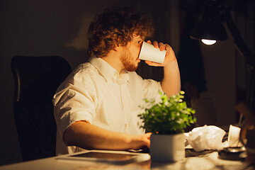 Image showing Man working in office alone during coronavirus or COVID-19 quarantine, staying to late night