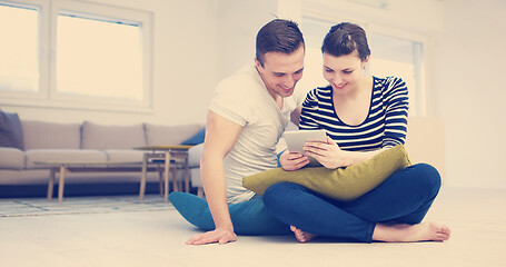 Image showing Young Couple using digital tablet on the floor