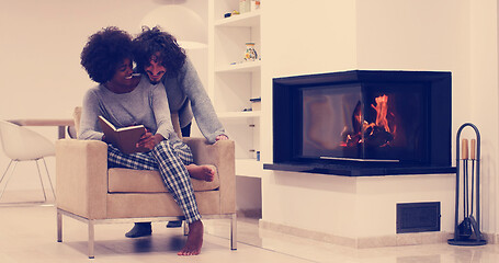 Image showing multiethnic couple hugging in front of fireplace