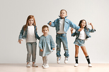 Image showing The portrait of cute little boy and girls in stylish jeans clothes looking at camera at studio