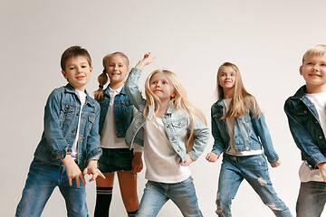 Image showing The portrait of cute little boy and girls in stylish jeans clothes looking at camera at studio