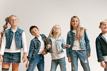 Image showing The portrait of cute little boy and girls in stylish jeans clothes looking at camera at studio