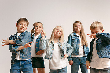 Image showing The portrait of cute little boy and girls in stylish jeans clothes looking at camera at studio