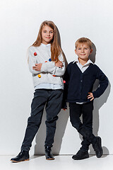 Image showing The portrait of cute little boy and girl in stylish jeans clothes looking at camera at studio