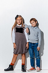 Image showing The portrait of cute little boy and girl in stylish jeans clothes looking at camera at studio