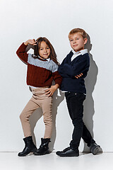 Image showing The portrait of cute little boy and girl in stylish jeans clothes looking at camera at studio