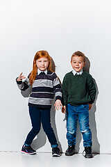 Image showing The portrait of cute little boy and girl in stylish jeans clothes looking at camera at studio