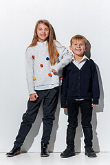 Image showing The portrait of cute little boy and girl in stylish jeans clothes looking at camera at studio