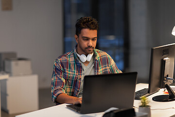 Image showing creative man with laptop working at night office